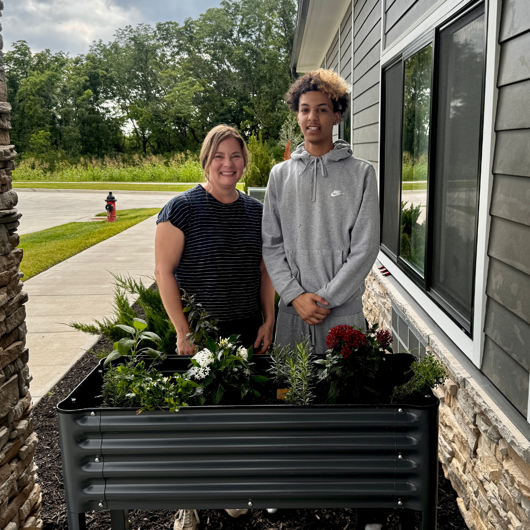 volunteer with youth in front of flower beds