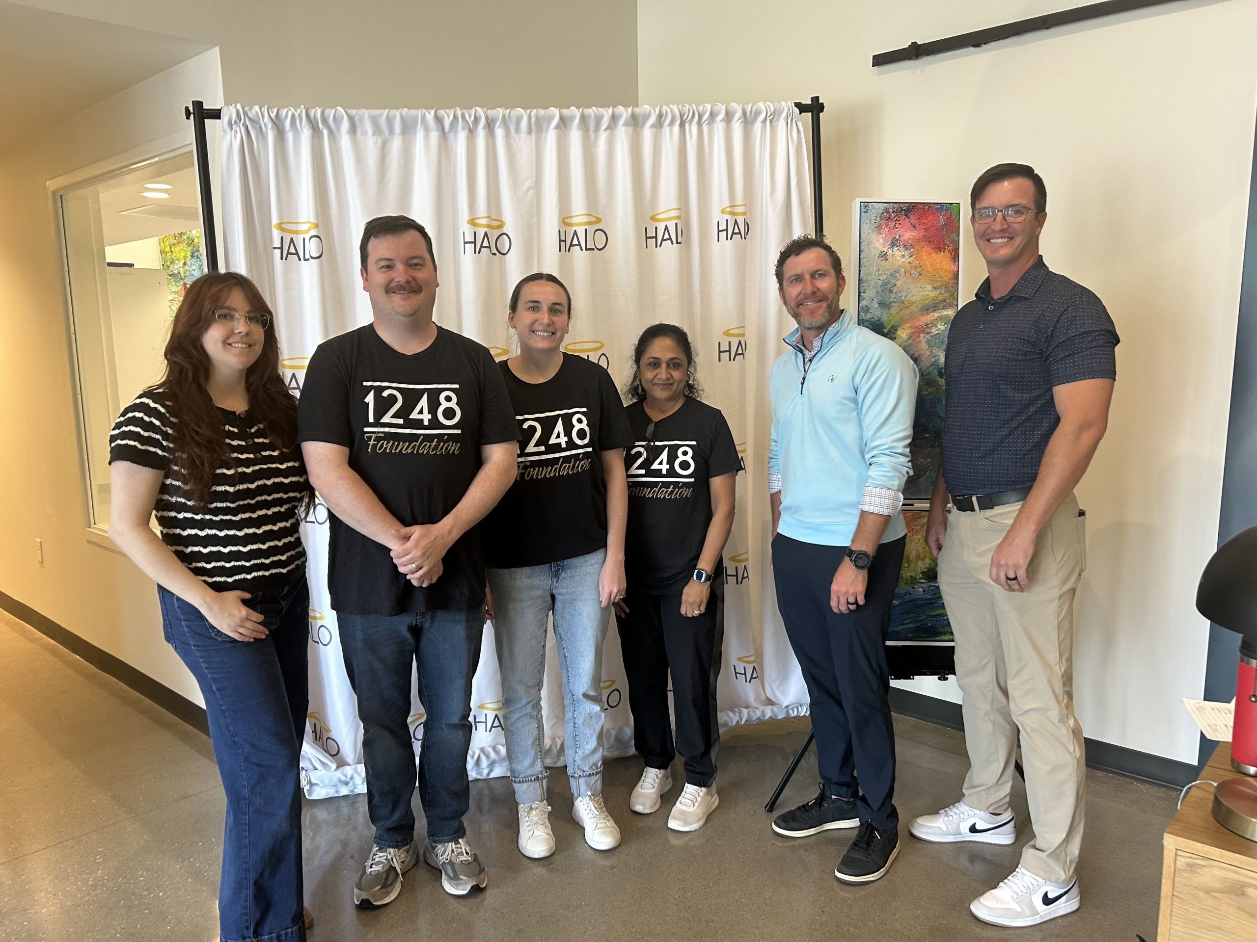 Staff and 1248 Foundation volunteers posing for a group photo in front of a HALO backdrop at a Member Event.